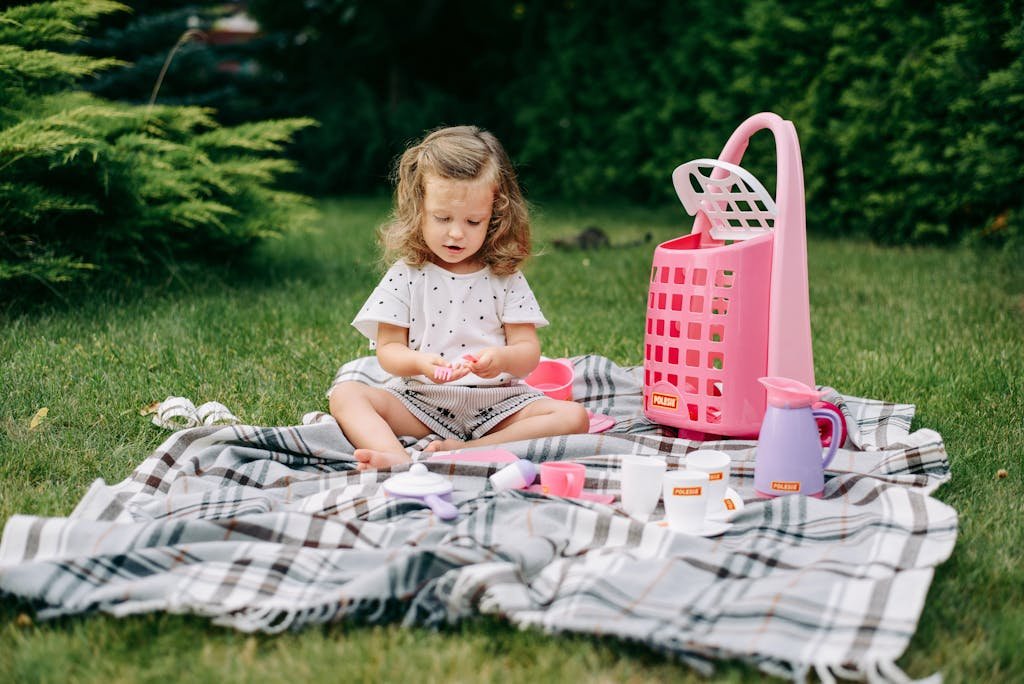 A young girl enjoying playtime with toys on grass, creating an idyllic childhood scene.